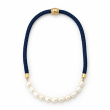 A necklace featuring a dark navy blue braided cord and a curved row of white baroque pearls, accented with gold-tone metal caps at the top and bottom, shown on a plain white background.