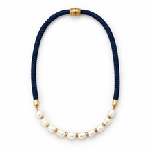A necklace featuring a dark navy blue braided cord, white freshwater pearls, and small gold spacer beads, finished with gold-toned metal caps on a white background.