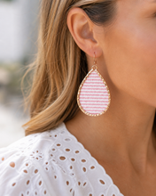 Close-up of a woman wearing pink striped earrings with gold accents.