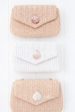 Three knitted purses with shell decorations on a white background
