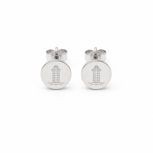 Pair of silver earrings with a harbor town lighthouse etched design on a white background