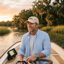 Man on a boat at sunset with trees and water in the background