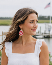 Woman wearing red and white checkered earrings by a waterfront