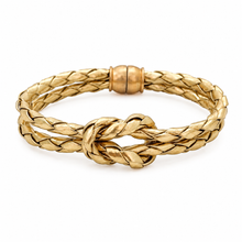A gold braided bracelet with a central knot detail and a smooth cylindrical clasp, shown on a clean white background.