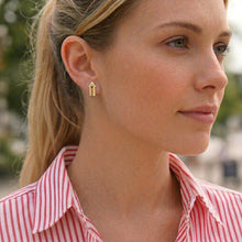 Woman wearing gold earrings with a blurred outdoor background