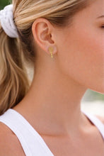 Close-up of a woman wearing gold earrings with a blurred background