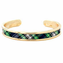 A gold-plated cuff bracelet featuring a central inlay of green, navy, white, and black tartan plaid fabric, shown against a plain white background.
