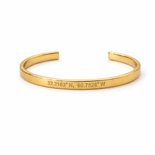 Gold bracelet with engraved coordinates on a white background