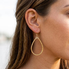 Gold hoop earring worn by a person with blurred background