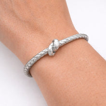 Silver braided bracelet on a wrist against a white background