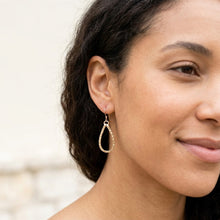 Close-up of a woman wearing a gold hoop earring with a blurred background