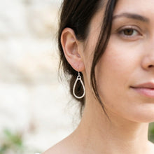 Close-up of a woman wearing a silver hoop earring with a blurred background