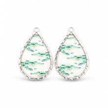 Small white teardrop pieces with green alligator motifs and silver-tone rims.