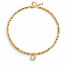 A gold-toned tubular collar necklace with a small oval clear gemstone pendant, displayed on a clean white background.