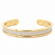 A gold-plated cuff bracelet featuring a textured, light-gray inlay band, photographed on a clean white background.