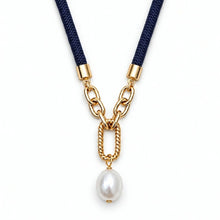 A gold chain necklace featuring a white baroque pearl pendant, suspended from a navy blue braided cord with gold metal connectors, shown on a plain white background.