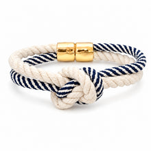 A nautical-themed rope bracelet featuring a cream and navy blue twisted rope with a knotted detail and a polished gold magnetic clasp, shown on a clean white background.