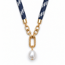 A necklace featuring a navy blue woven strap with white geometric patterns, connected via gold-tone chain links to a single dangling white pearl, shown on a plain white background.