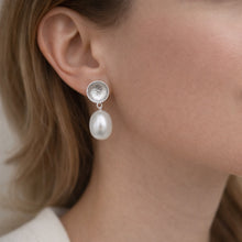 Close-up of a woman wearing pearl and crystal earrings.