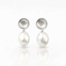 Pair of silver earrings with round pearls on a white background