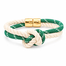 A double-strand rope bracelet featuring a green and off-white woven pattern, tied in a knot with polished gold-colored metal cylinder clasps, shown on a clean white background.