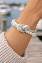 Nautical-style bracelet on a wrist with a blurred waterfront background