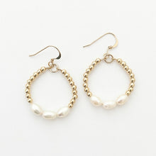 Gold hoop earrings with pearl-like beads on a white background