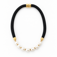 A black braided cord necklace with a curved row of white freshwater pearls separated by small gold spacer beads, finished with gold metal end caps on a white background.
