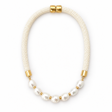A necklace featuring a cream-colored braided cord, a row of white baroque pearls separated by small gold spacer beads, and polished gold end caps, shown on a plain white background.