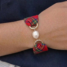 Bracelet with plaid fabric and pearl bead on wrist against a dark shirt and light pants background