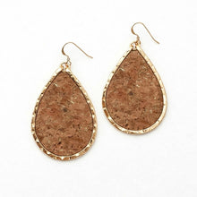 Teardrop-shaped earrings with cork texture and gold frame on a white background