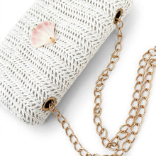 Gold chain necklace with a textured white handbag on a light background