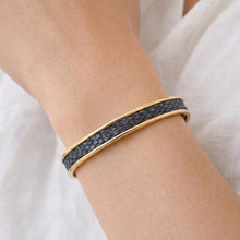 Gold bracelet with black stones on a wrist against a white background
