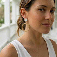 Woman wearing gold hoop earrings with a blurred background