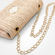 Gold chain necklace on a textured beige surface