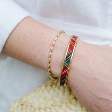 Close-up of a wrist wearing two bracelets on a white background heritage plaid pga golf tournament bracelet
