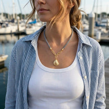 Woman wearing a gold necklace with a marina in the background