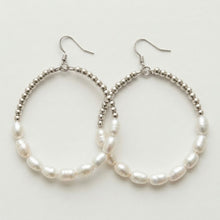 Pearl hoop earrings with silver beaded accents on a light gray background