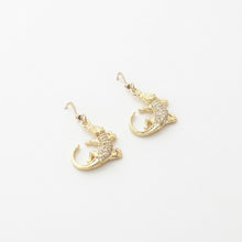 Gold lizard-shaped earrings on a white background