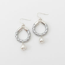 Silver hoop earrings with pearl drops on a white background