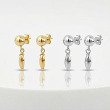 Pair of gold and silver earrings on a white background