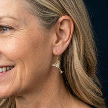 Close-up of a woman wearing gold earrings with a dark background