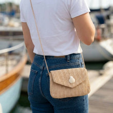 Person wearing a beige knitted bag with a blurred background of boats