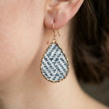 Teardrop-shaped earring with geometric pattern worn by a person