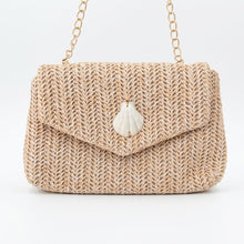 Woven handbag with a shell charm on a white background