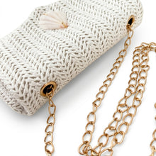Beige textured handbag with gold chain and shell accessory on a white background