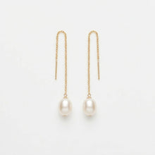 Gold chain earrings with pearl drops on a light gray background