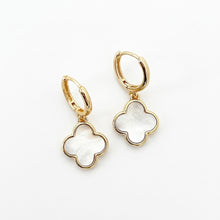Gold hoop earrings with clover-shaped white stones on a white background