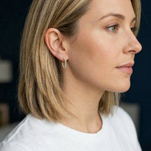 Close-up of a woman wearing a silver hoop earring with a blurred background