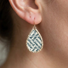 Teardrop-shaped earring with a geometric pattern worn by a person.